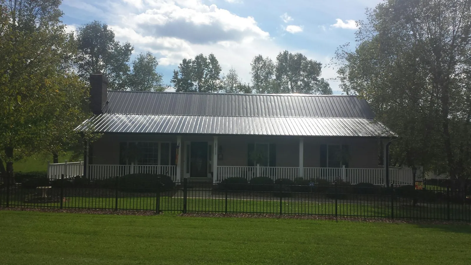 Gray metal roof on a brick ranch with a full width front porch — Gutter Guard Installation work by our crew in Sunset Beach