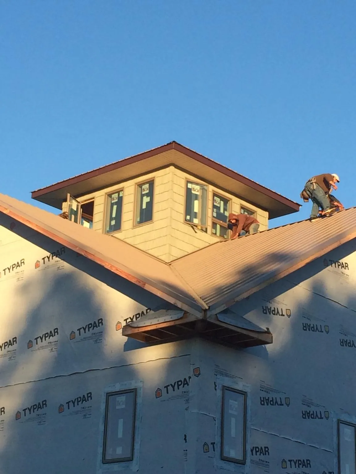 Roofers working around a rooftop cupola on a new metal roof at sunset — Roof Waterproofing in Sunset Beach by Roofing Brothers